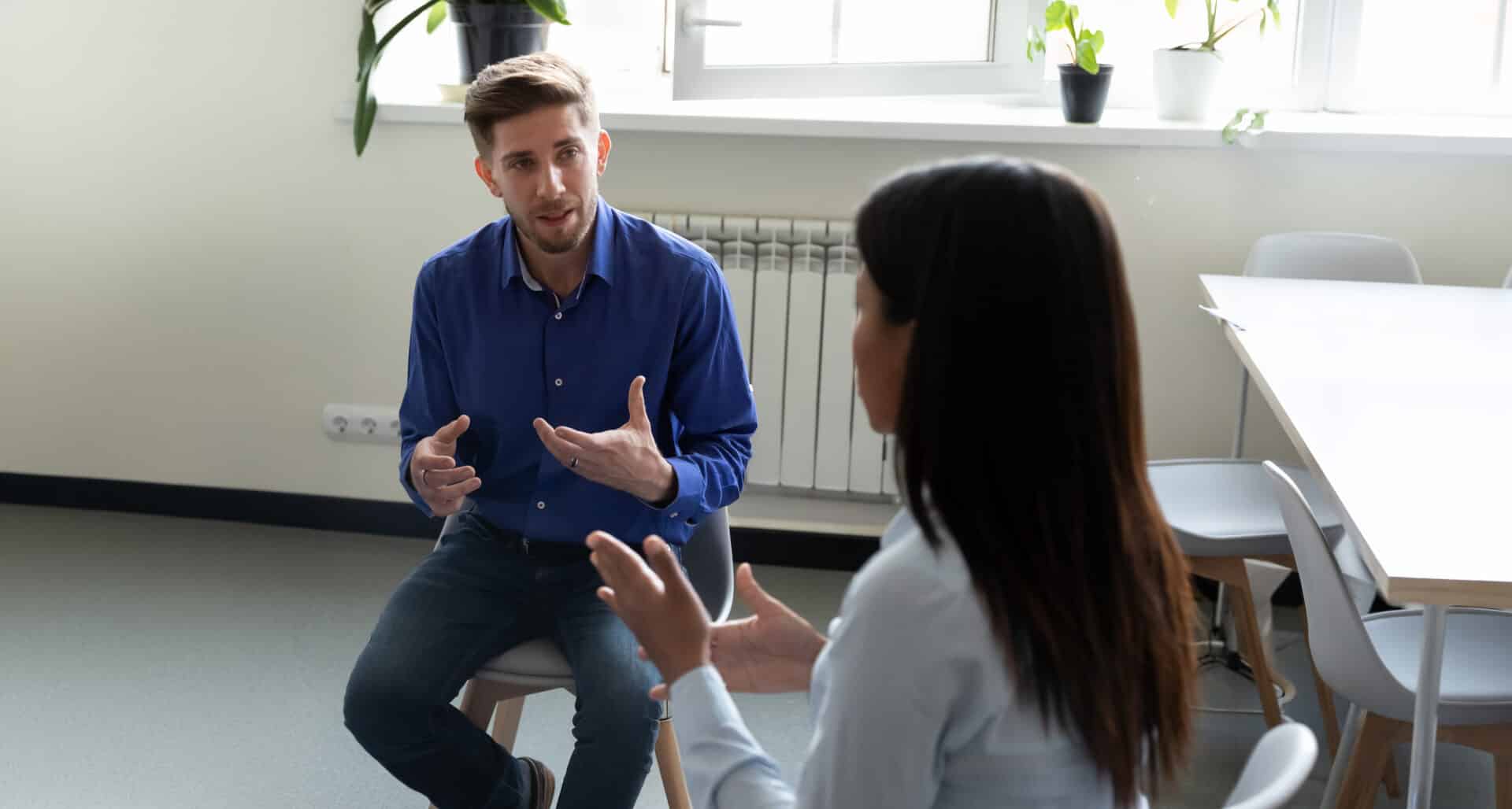 Leidinggevende in gesprek met een medewerker in een rustige werksetting.